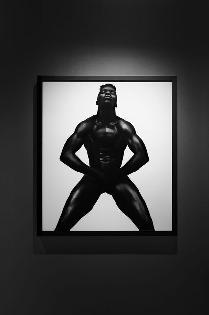 An exhibition place with green-teal background, showcasing a black-teal sculpture made by Peter Schlesinger.