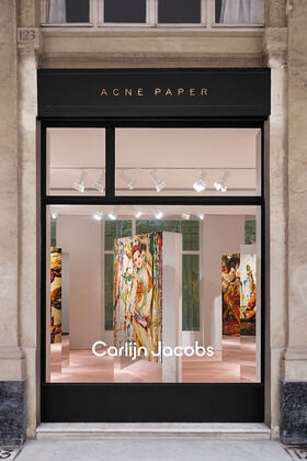 Exterior window of the Acne Paper Palais Royal gallery space in Paris, presenting the permanent gallery that merges fashion, art, and publishing beneath the Palais Royal arcades.
