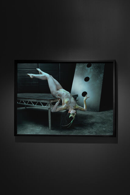 An exhibition place with green-teal background, showcasing a grey massive sculpture made by Peter Schlesinger.