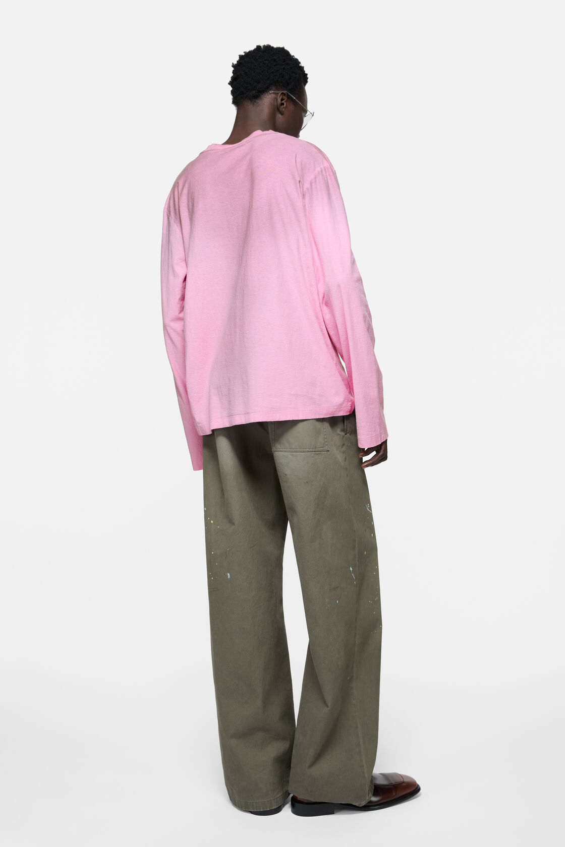 Acne Studios cotton candy pink long-sleeve crewneck t-shirt in a relaxed fit, worn with sage green wide-leg jeans and a dark brown tote bag.