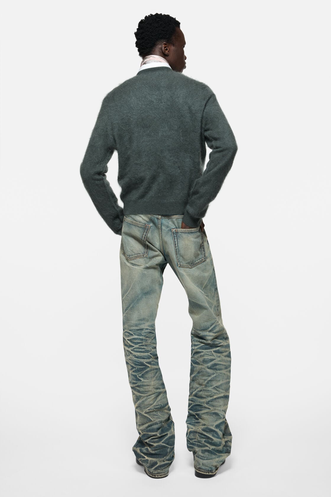 Acne Studios dark green cashmere v-neck sweater with fuzzy texture, worn from behind with light-wash distressed denim jeans and a scarf.