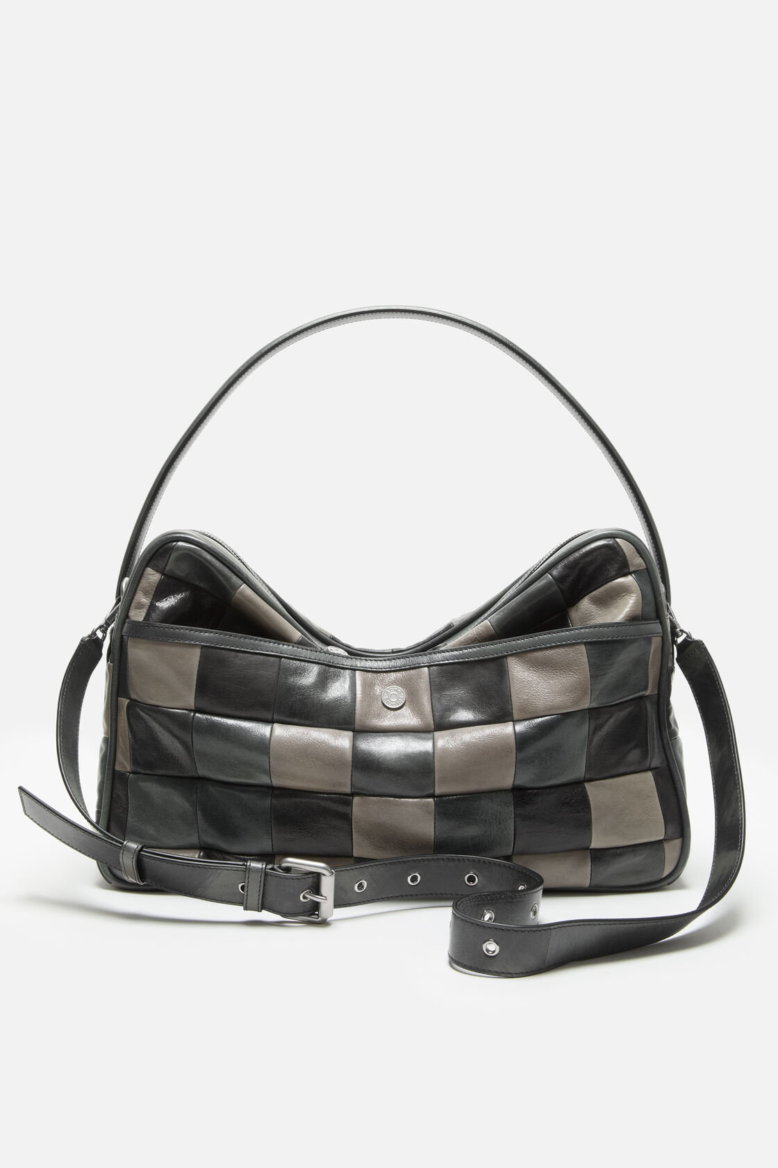 Close-up of an Acne Studios Camero Camera Bag in dark grey and black patchwork leather, showing two branded silver snap buttons on a strap.