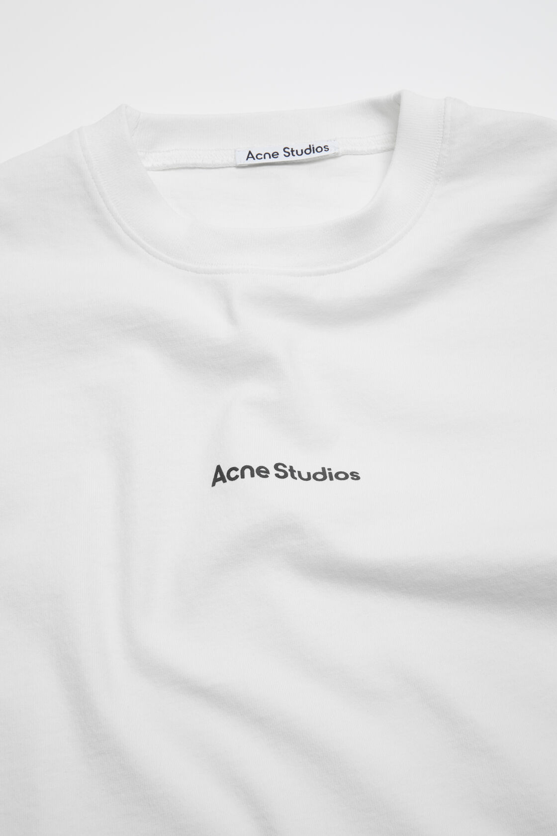 Acne Studios optic white relaxed fit crew neck t-shirt with small stamp logo printed at chest center.
