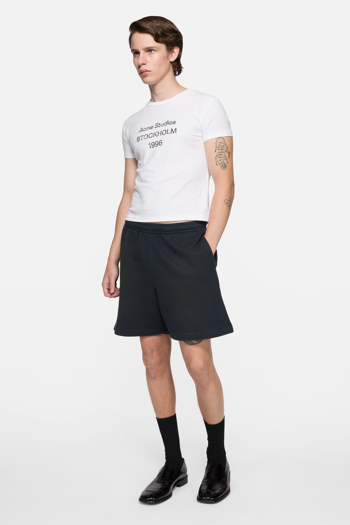 Acne Studios off-white logo T-shirt with crew neck, printed branding at chest, worn with black leather trousers and black shoes.