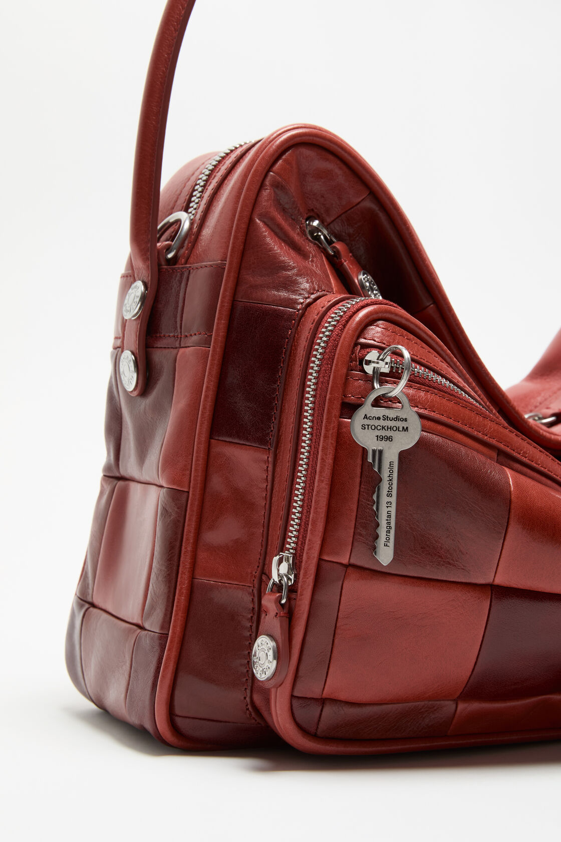 Close-up of an Acne Studios Camero camera bag interior in burgundy leather, showing the open zip compartment, branded leather label, and black
