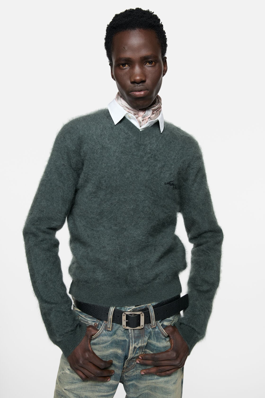 Acne Studios dark green cashmere v-neck sweater with fuzzy texture, worn over a white collar shirt with a light pink scarf, styled with light wash
