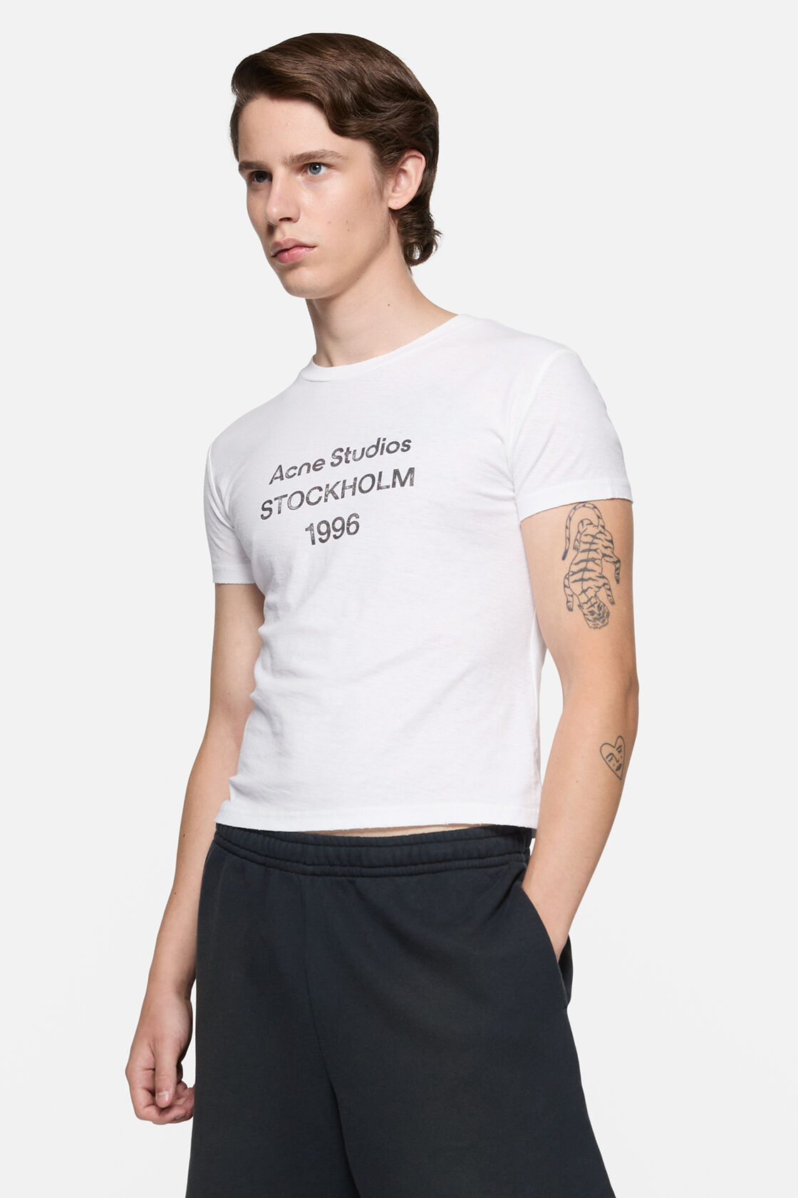 Acne Studios off-white logo T-shirt with crew neck, printed branding at chest, worn with black leather trousers and black shoes.