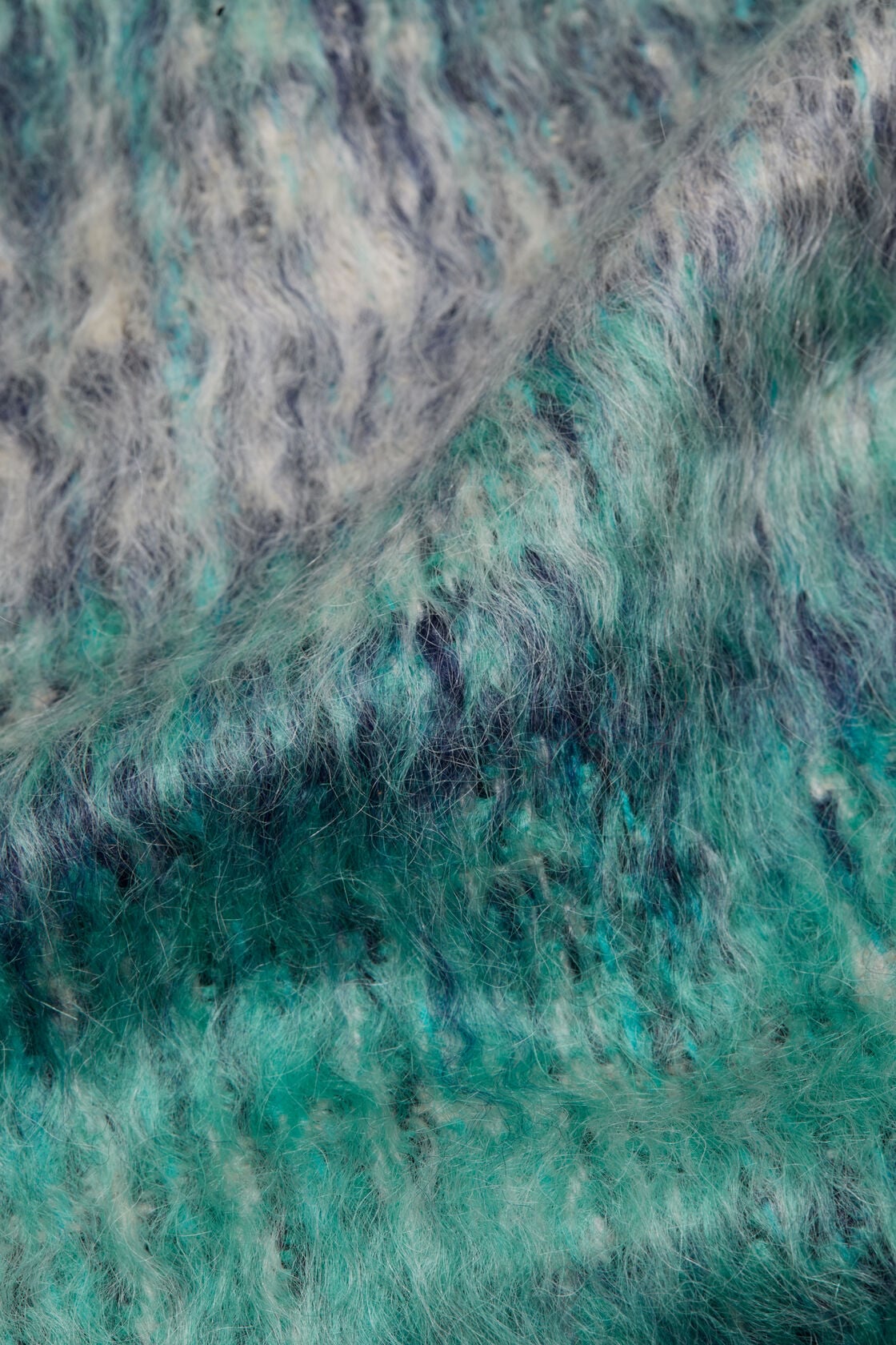 Close-up of an Acne Studios fringed mohair scarf in a white and aqua multicolour fuzzy texture.