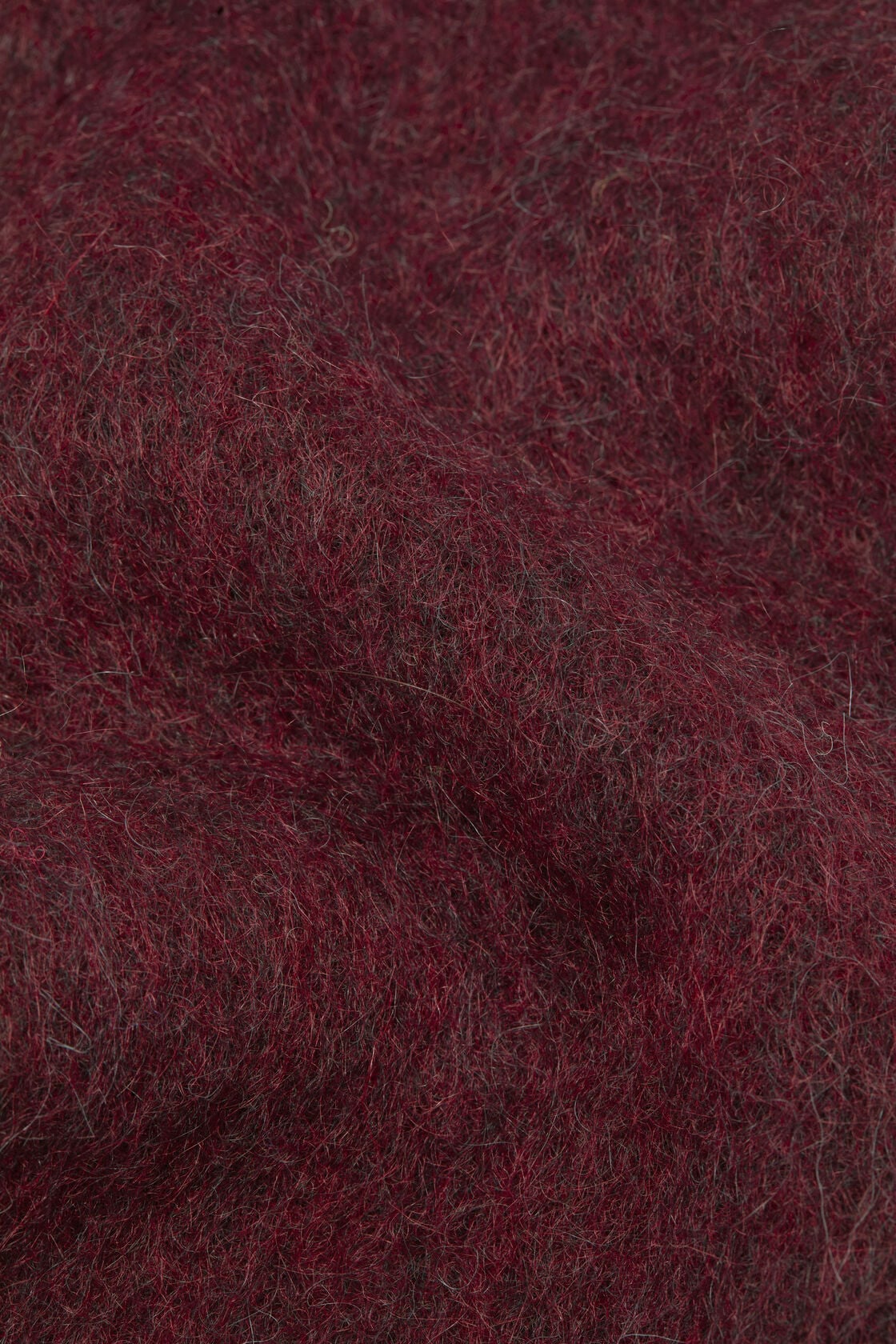 Close-up of an Acne Studios skinny mohair scarf in burgundy, showing the fluffy, textured surface of the mohair-wool blend fabric.