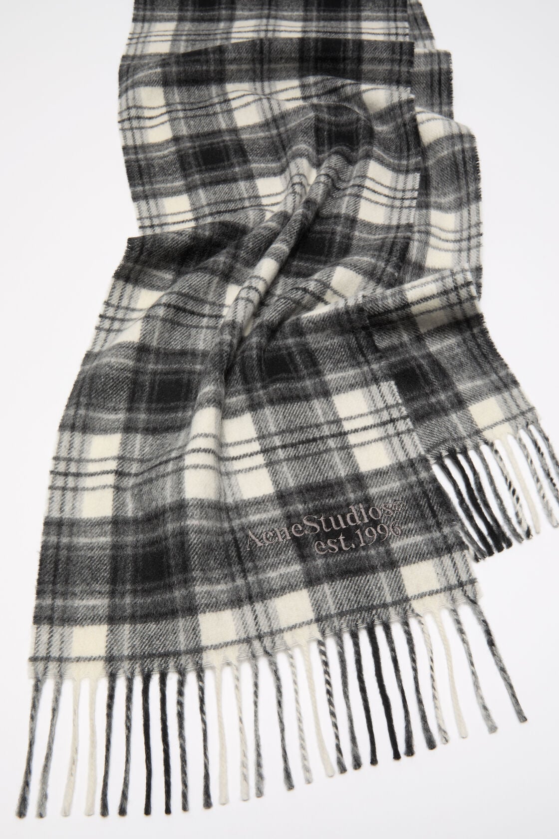 Acne Studios cashmere scarf in black and white plaid check with twisted fringe ends and embroidered logo detail.