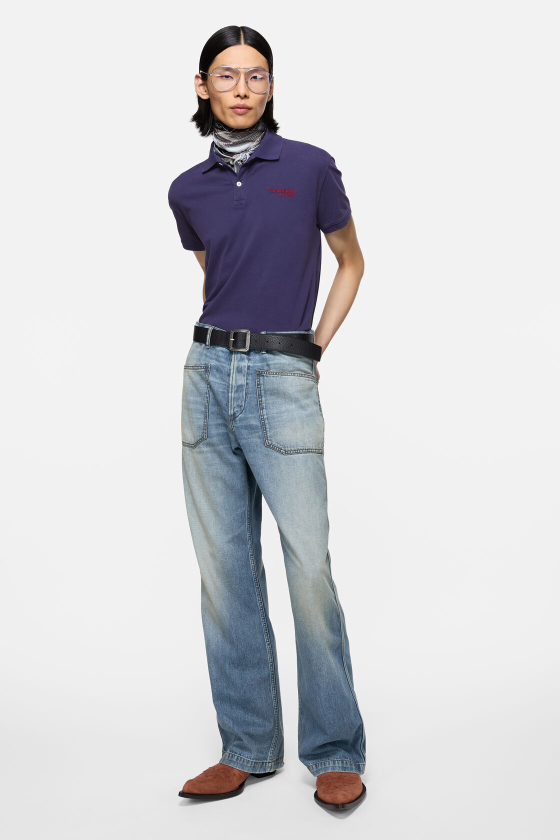 Acne Studios mid blue regular-fit denim trousers with a straight leg and slight flare, worn with a navy polo shirt and brown boots.