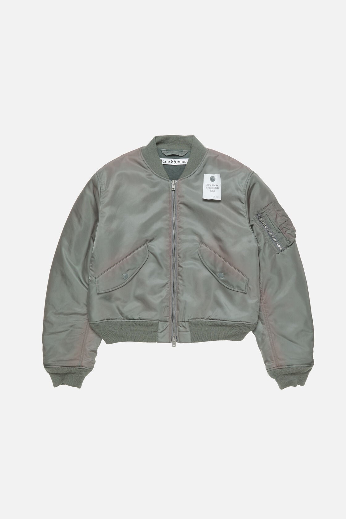 Acne Studios stone grey washed bomber jacket in recycled nylon, ribbed trim, flap pockets, and sleeve zip pocket.