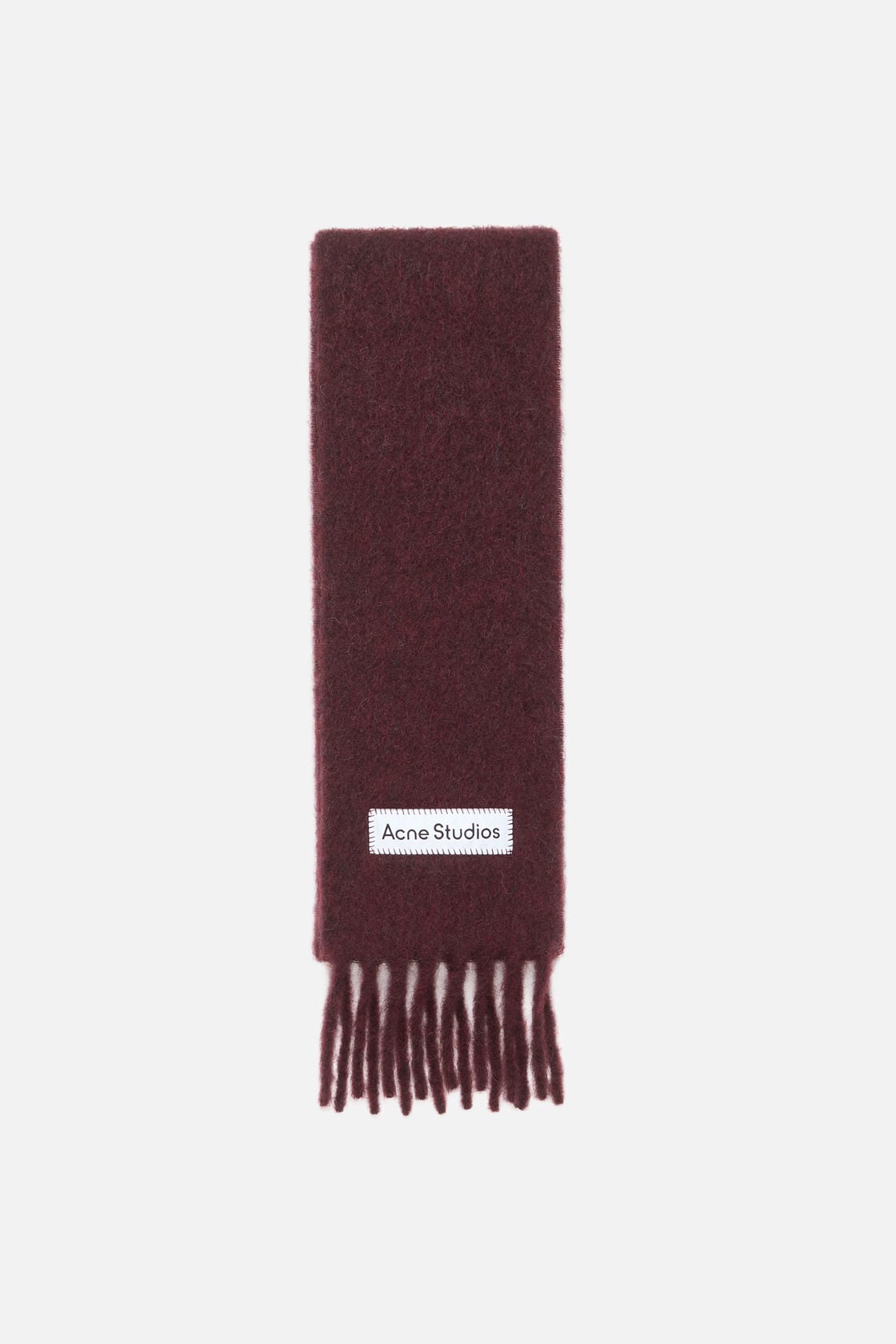 Acne Studios skinny scarf in burgundy mohair-wool blend with a fuzzy texture, fringed ends, and a blanket-stitched satin logo label.