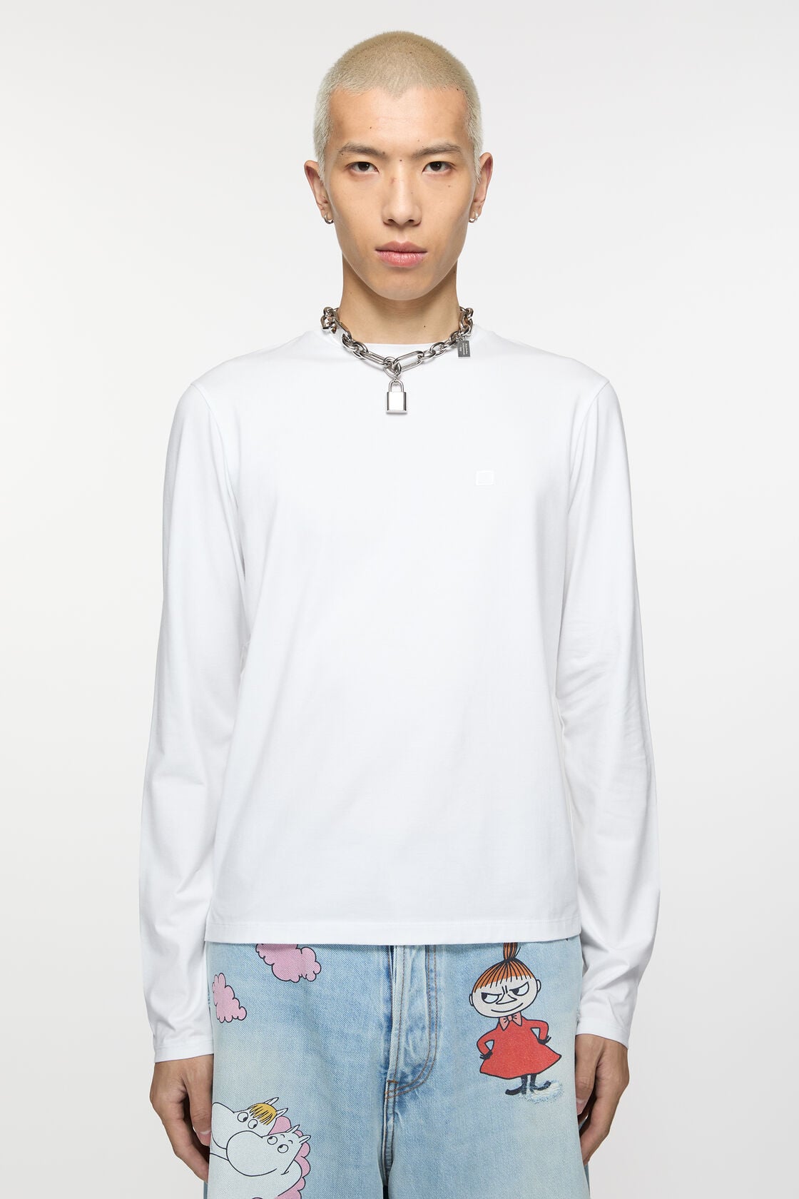 Close-up of an Acne Studios optic white long sleeve t-shirt in regular fit, showing a tonal embossed Face logo patch on soft stretch fabric.