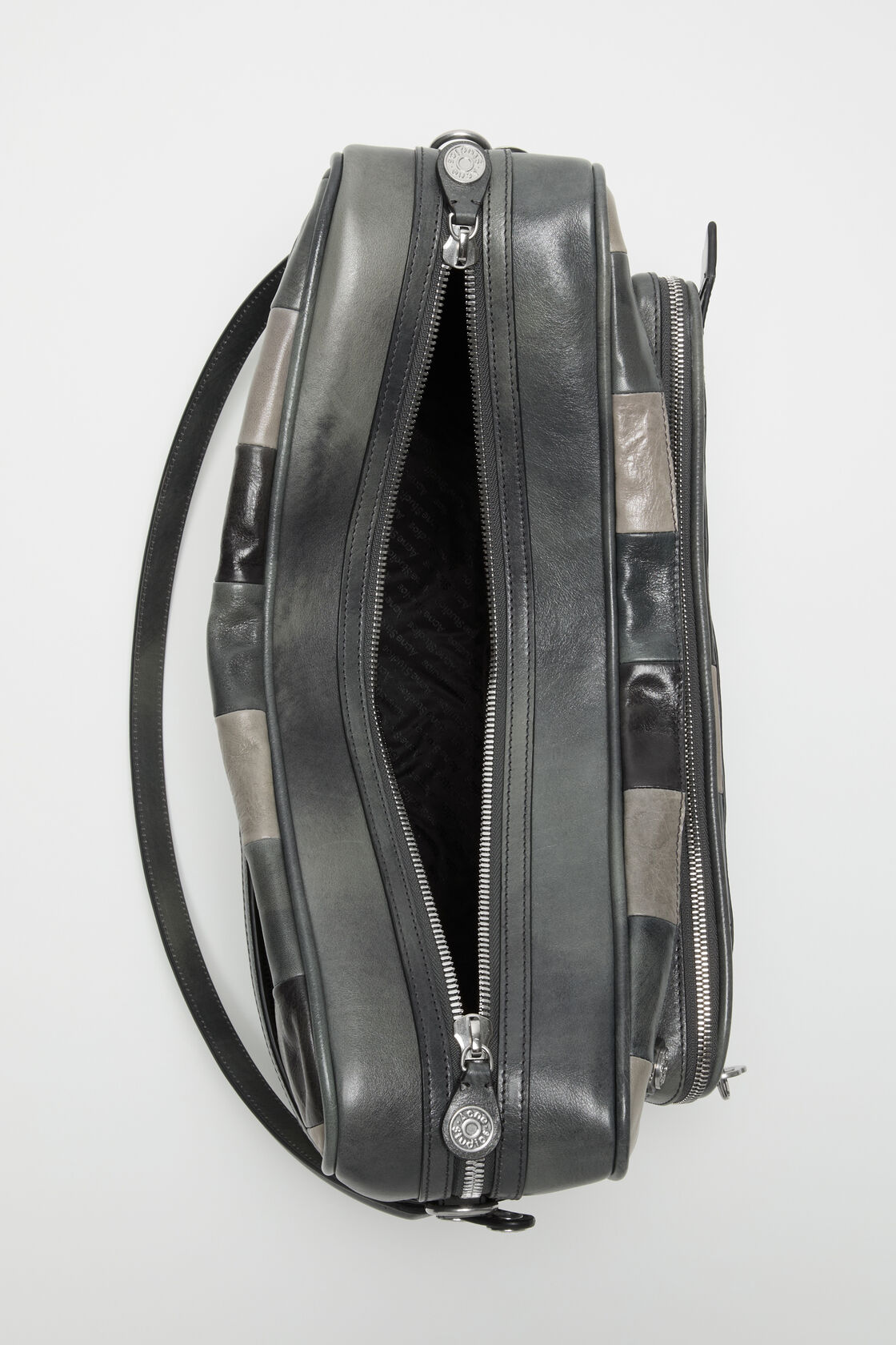 Close-up of an Acne Studios Camero Camera dark grey patchwork leather bag with silver zip closures and a branded key charm.