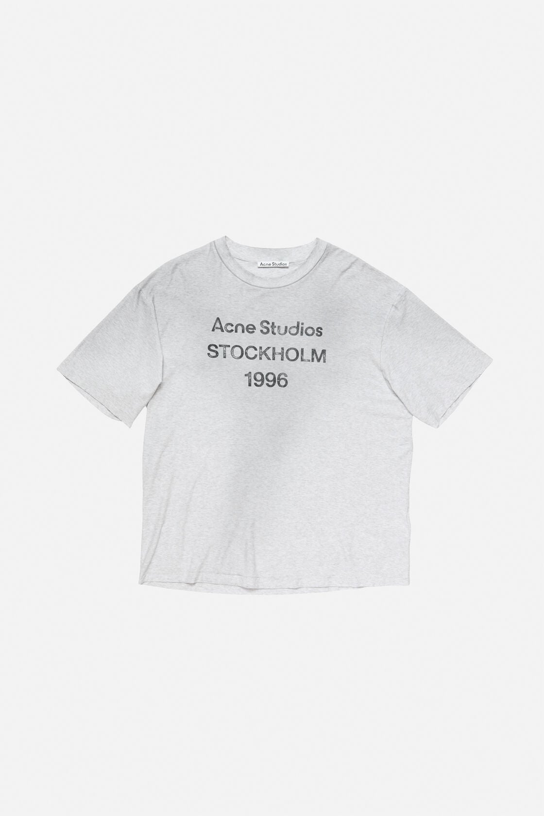 Acne Studios pale grey melange sprayed logo t-shirt in a relaxed fit, worn with light wash distressed wide-leg jeans and dark loafers.
