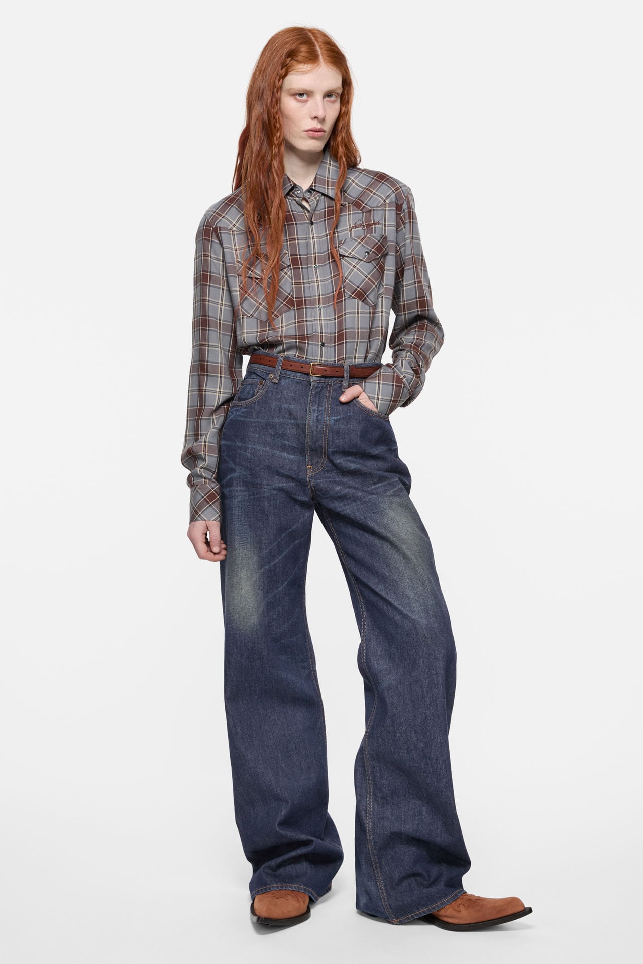 Acne Studios Womenswear blue-brown checked shirt, blue jeans with a brown belt.