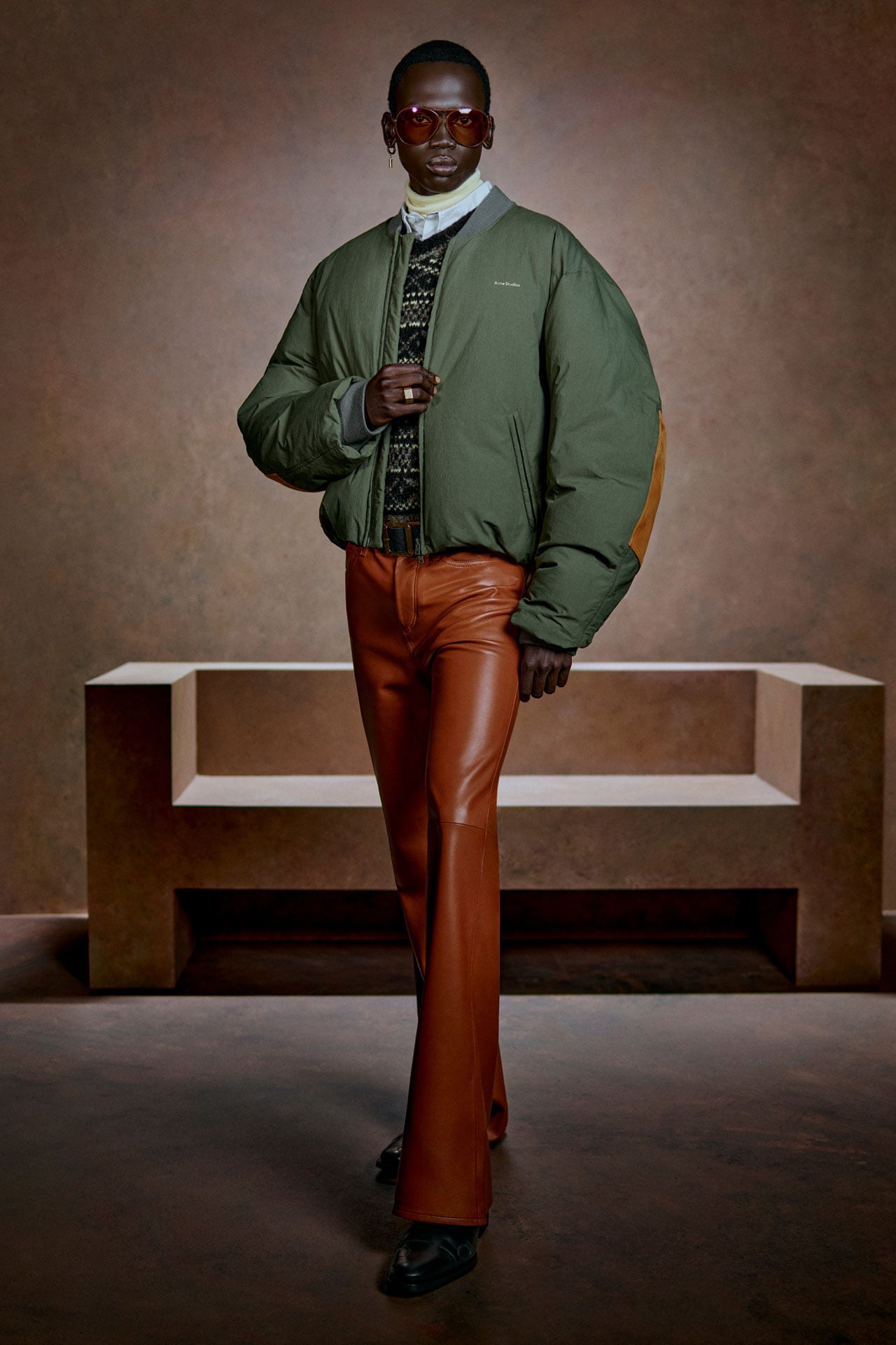 Acne Studios Menswear green puffer bomber jacket and brown leather pants.