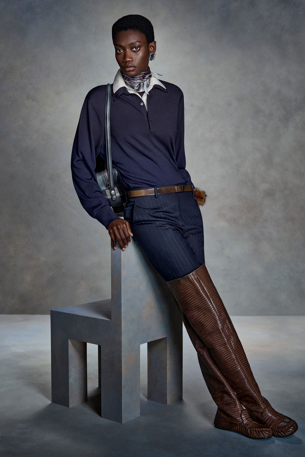 Acne Studios navy blue long-sleeve top and navy pants, and over-the-knee brown leather boots.