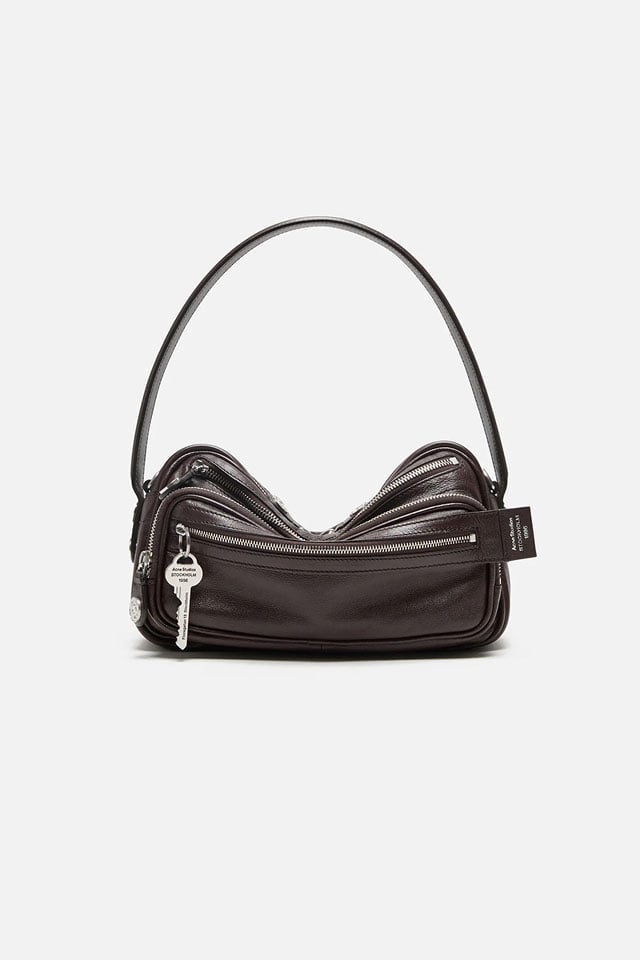 A showcase of the product of Acne Studios Camero Party shoulder bag in brown, with silver details and a silver key detail.
