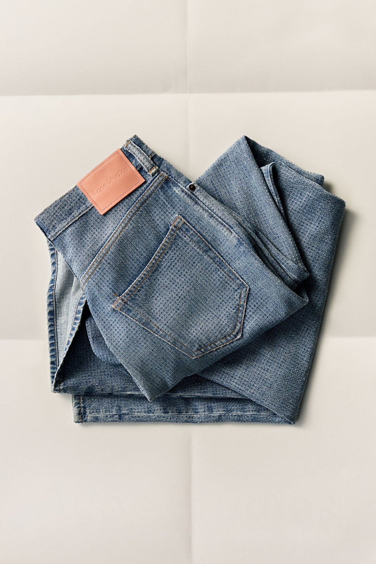 Acne Studios FW25 Gift Guide collection, a pair of blue jeans with rhinestones folded on white paper.