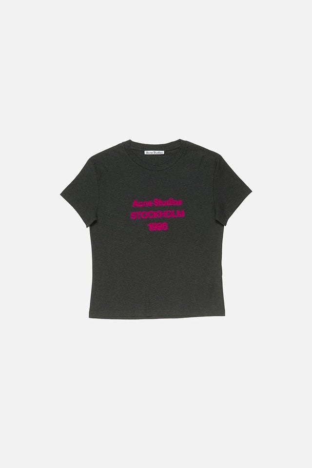 A showcase of the product of Acne Studios black t-shirt with fuschia logo on it.