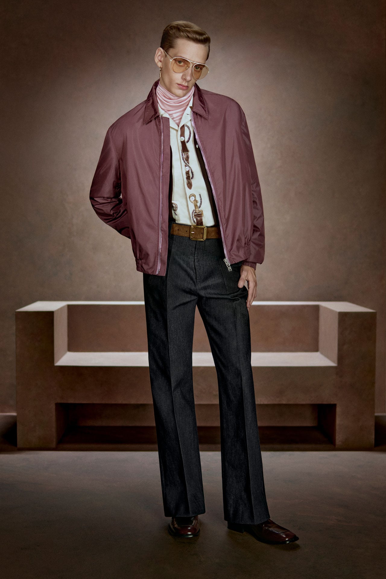 Acne Studios Menswear lilac nylon jacket, brown leather belt, black tailored pants, white printed shirt and sunglasses.