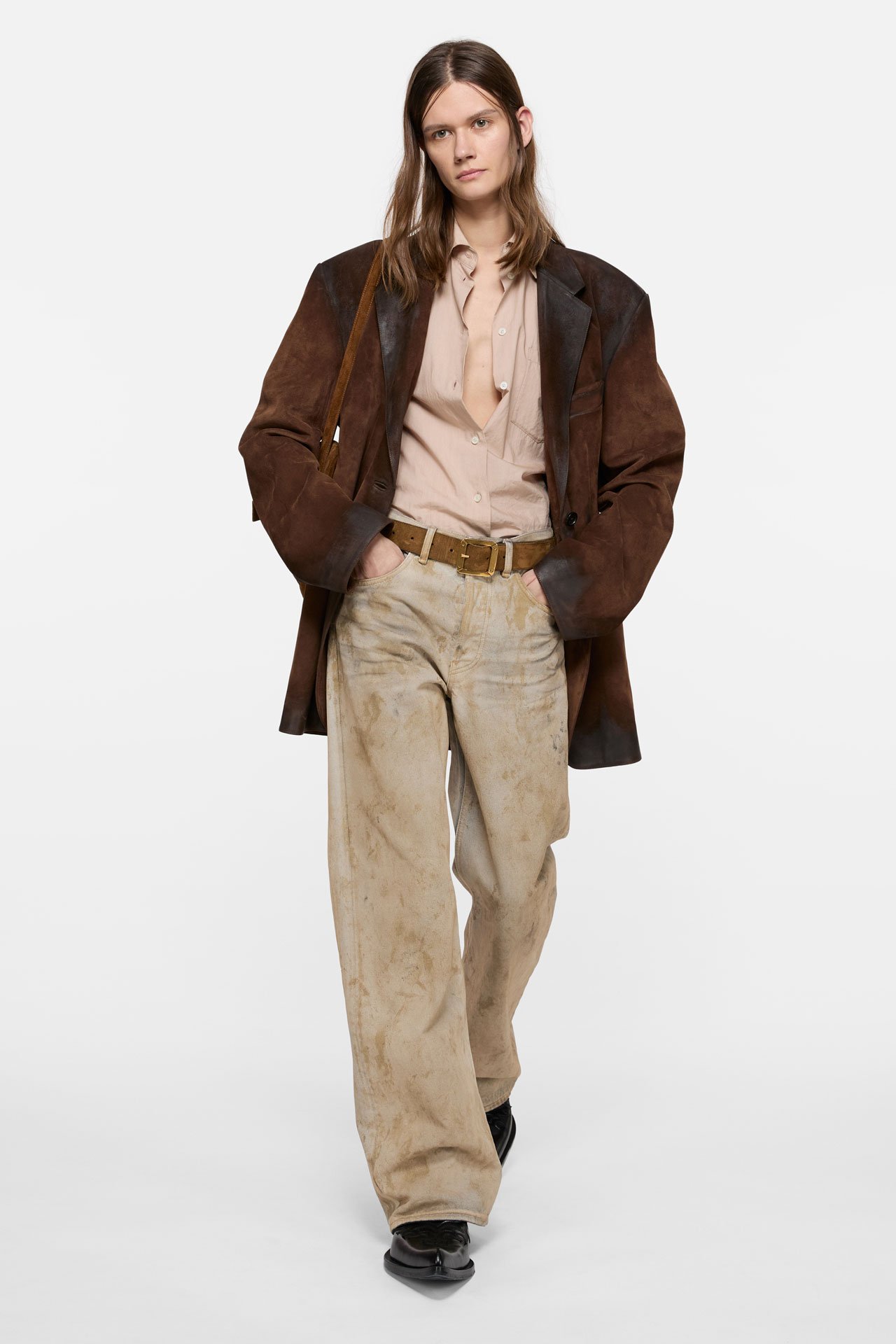 A female model wearing a sand-colored Acne Studios regular fit jeans in 2021F style, big brown leather jacket and beige shirt.