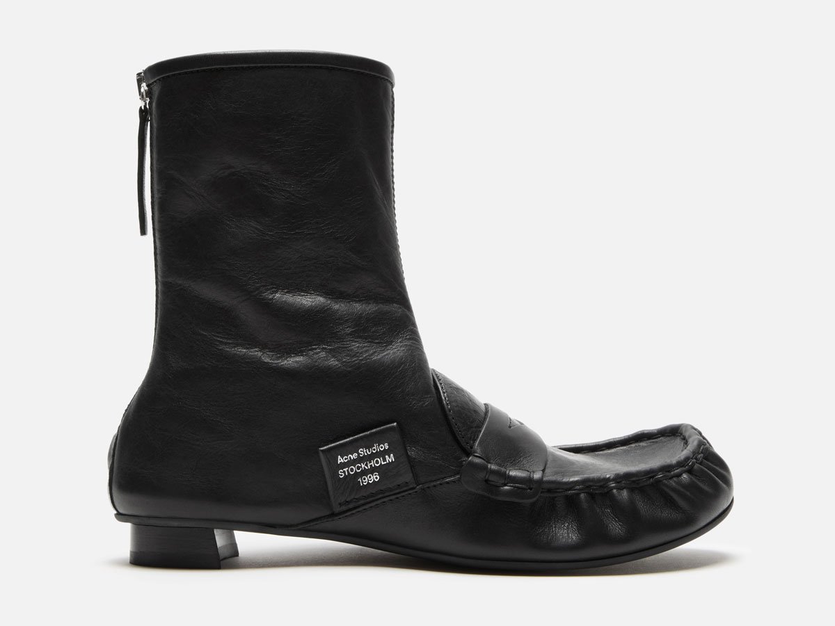 A close-up of the Acne Studios black leather ankle boots with details.