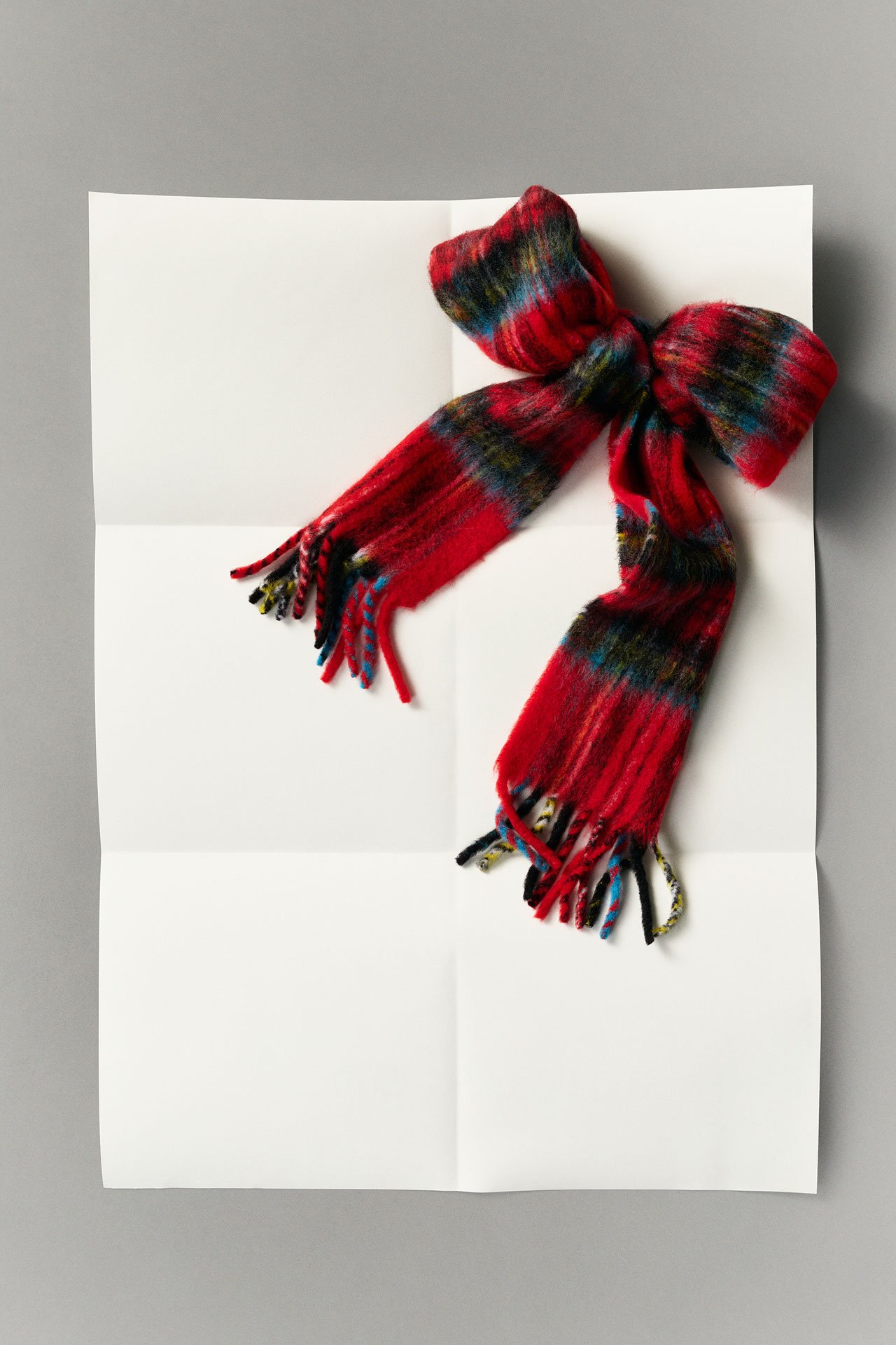 Acne Studios FW25 Gift Guide collection, red mohair check scarf tied in a bow on white paper.