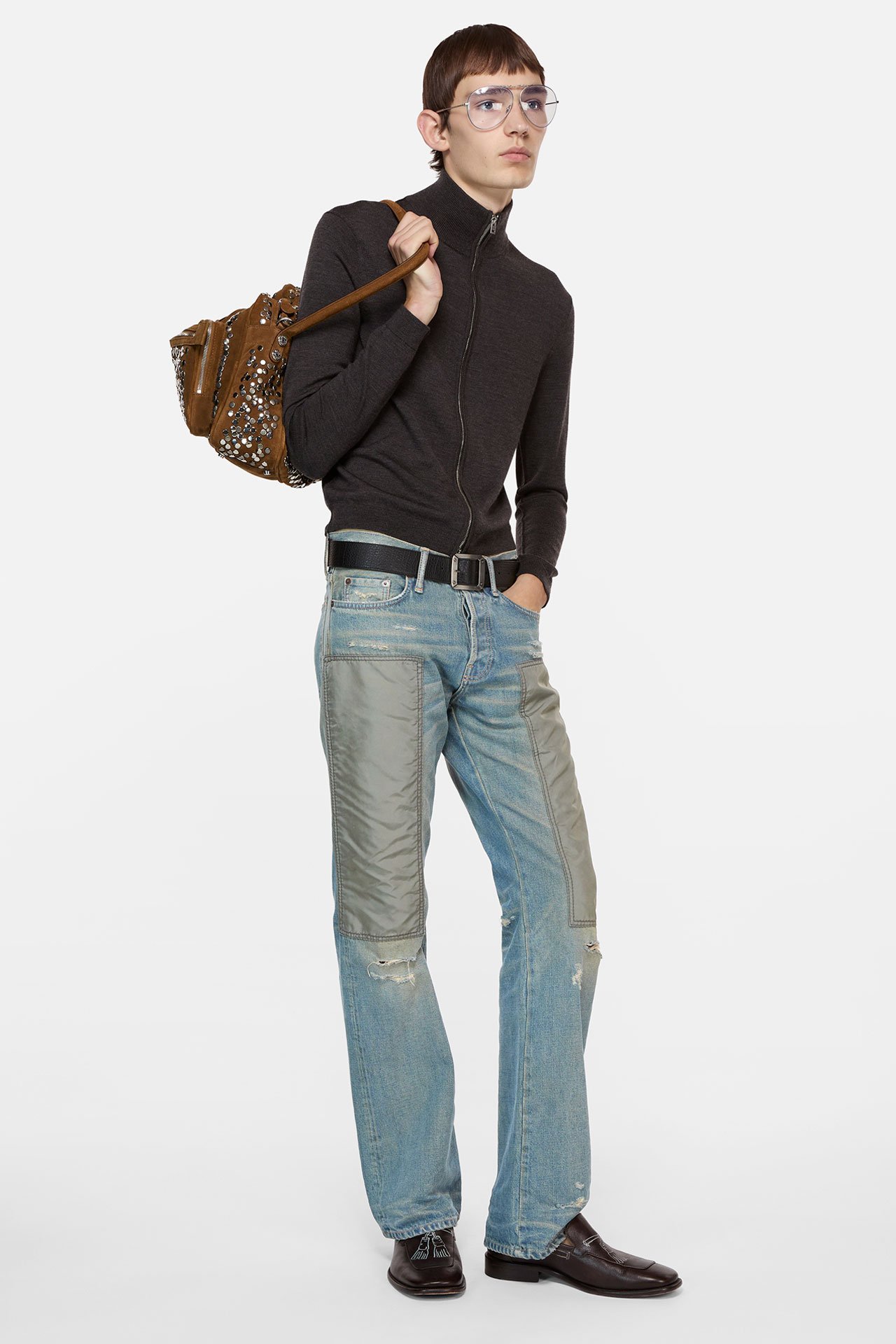 Male model showing Acne Studios new arrivals, wearing merino wool dark brown knitted cardigan, light blue jeans and a big Camero bag.