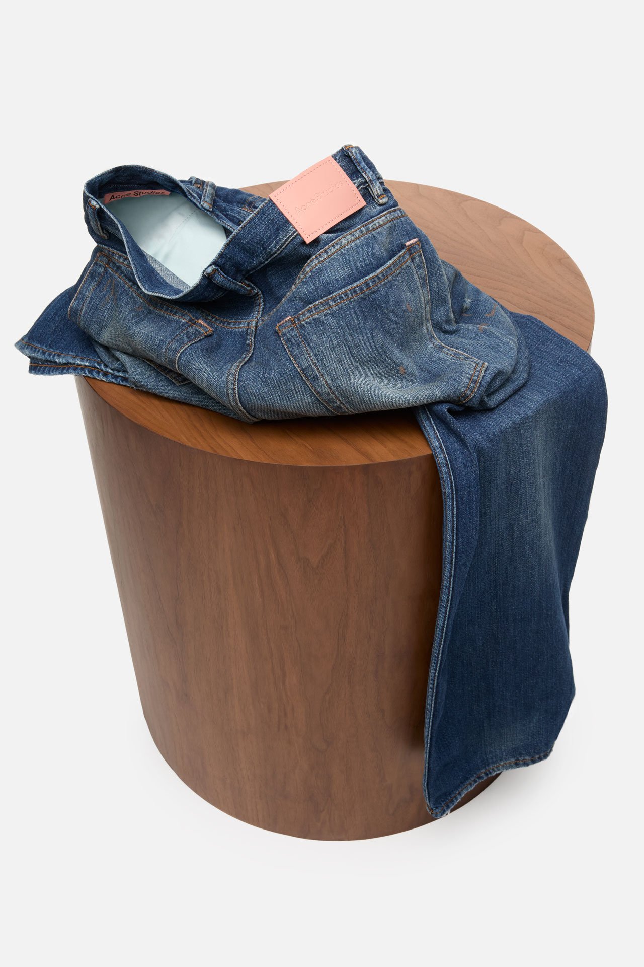 A creative showcase of the iconic Acne Studios blue jeans folded on a wooden pedestral.