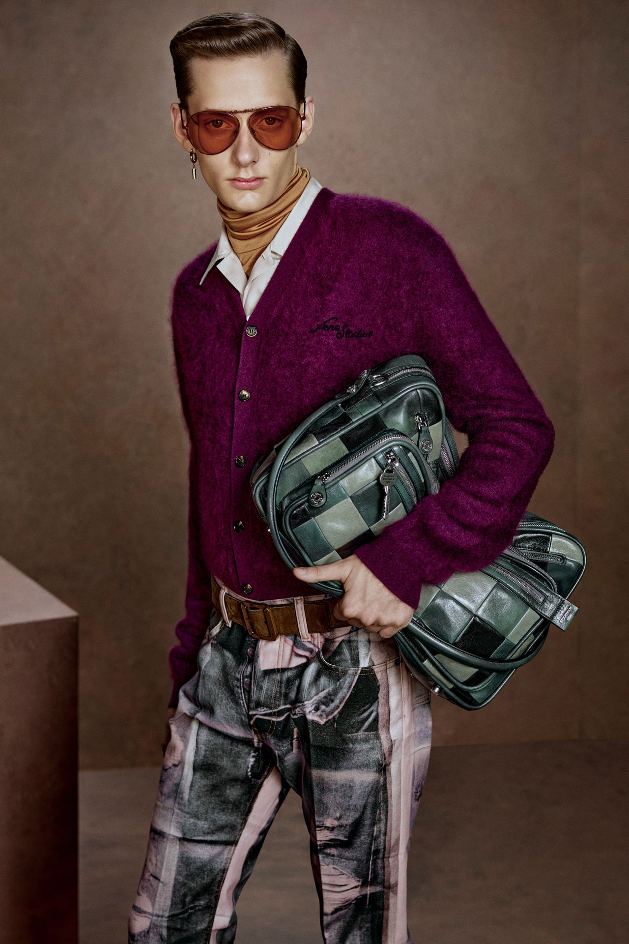 Acne Studios Menswear fuscia pink knitted cardigan, pink-black TLO jeans, green checked leather Camero bag and aviator sunglasses.