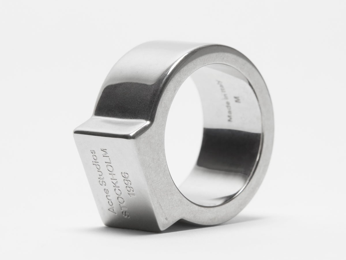 A close-up of the Acne Studios chunky slver ring with logo details.