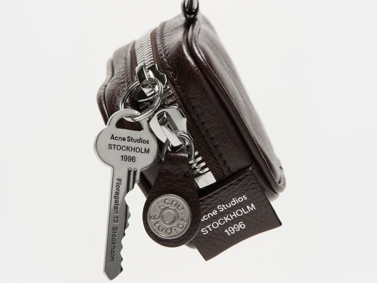 A close-up of the Acne Studios mini leather Camero bag in brown, with silver details.