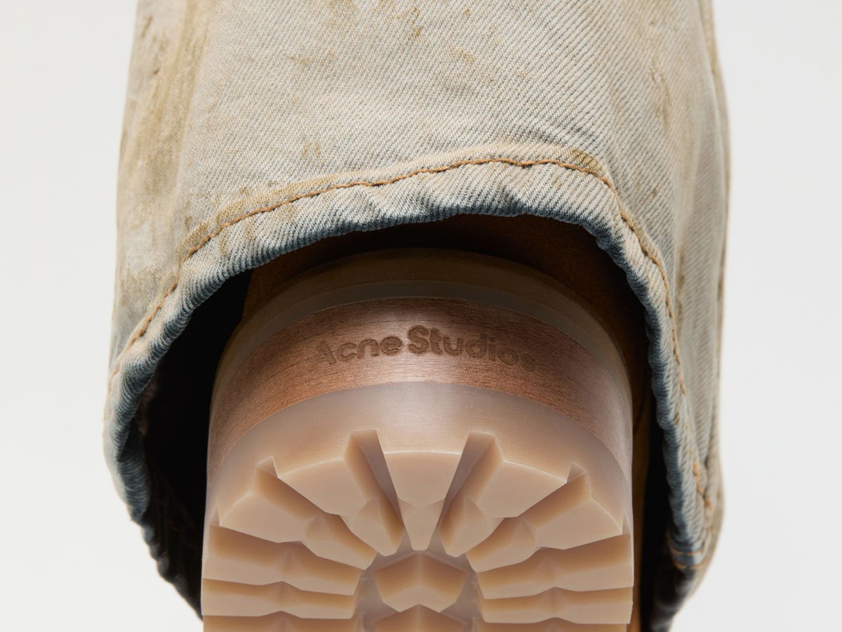 A close-up of the Acne Studios brown folded denim boots with a bit of light beige jeans on top of them.