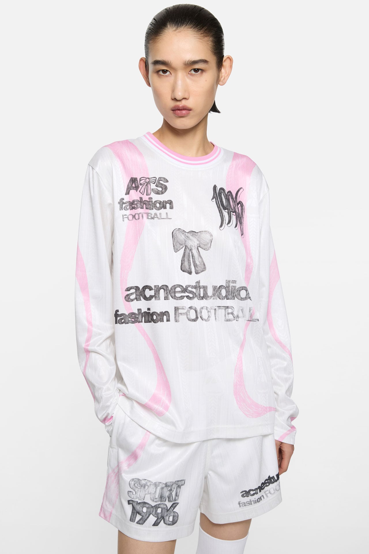 Female model wearing Acne Studios SS26 Football Capsule white-pink matching long-sleeved t-shirt and shorts.