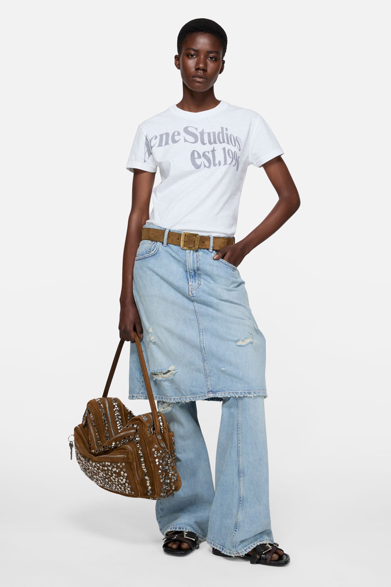 Female model wearing a white shirt, light blue skirt-jeans, holding a brown suede Camero bag.