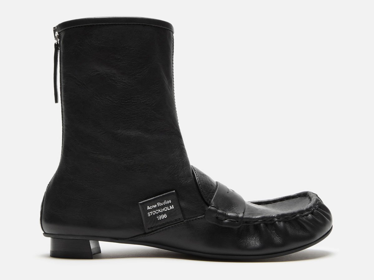 A close-up of the Acne Studios black leather ankle boots with details.