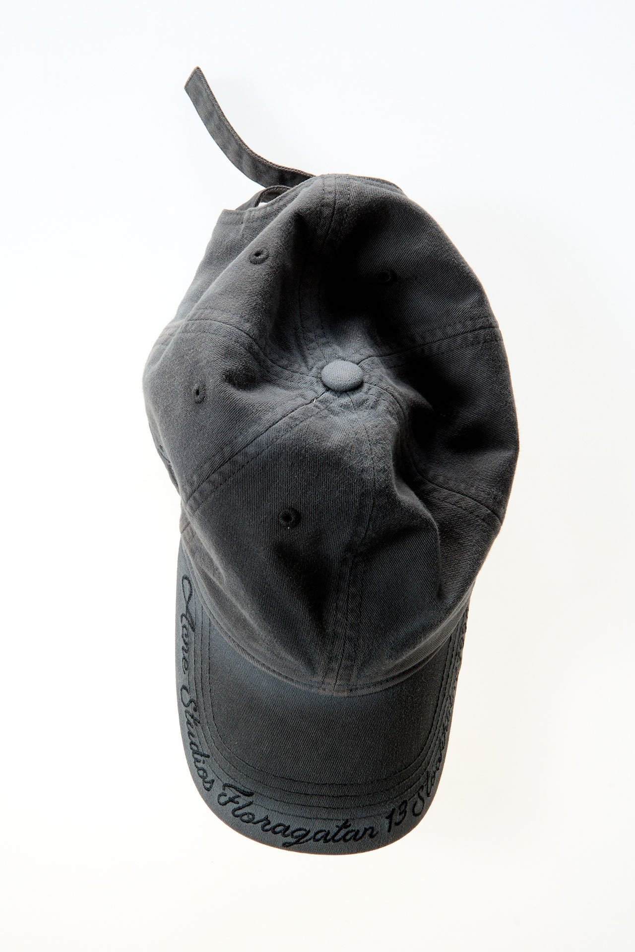 A creative product image of the Acne Studios faded grey cap with text details.