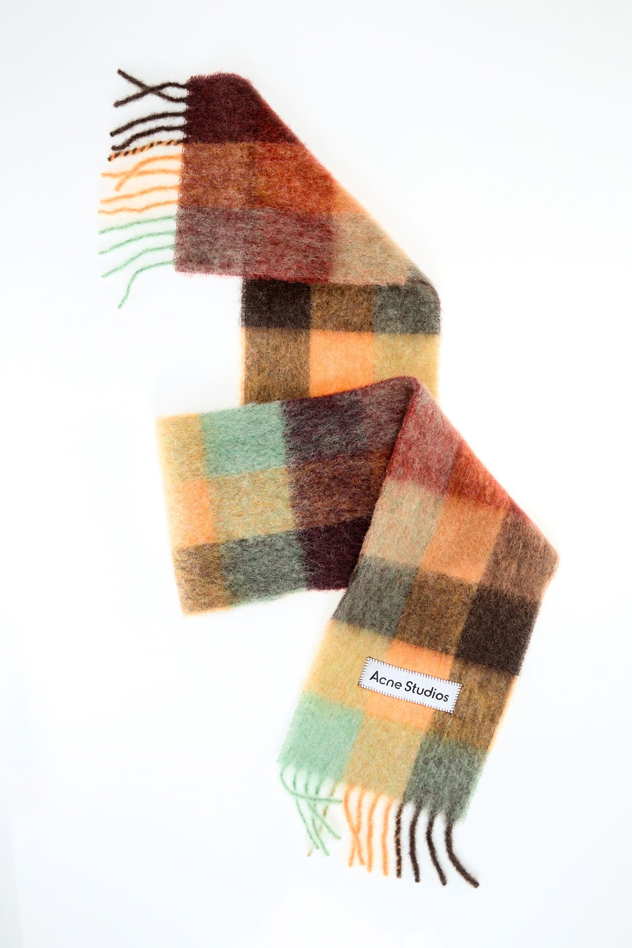 A creative product image of the Acne Studios Vally mohair checked scarf in chestnut brown, jellow and green colors.