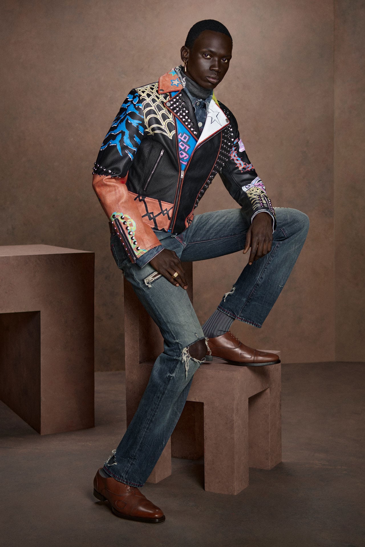 Acne Studios colorful leather jacket, ripped jeans and brown leather shoes.