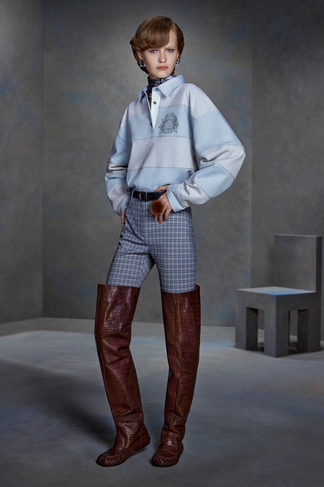 Acne Studios Womenswear light blue striped sweater, blue checked pants and brown leather over-the-knee high boots.