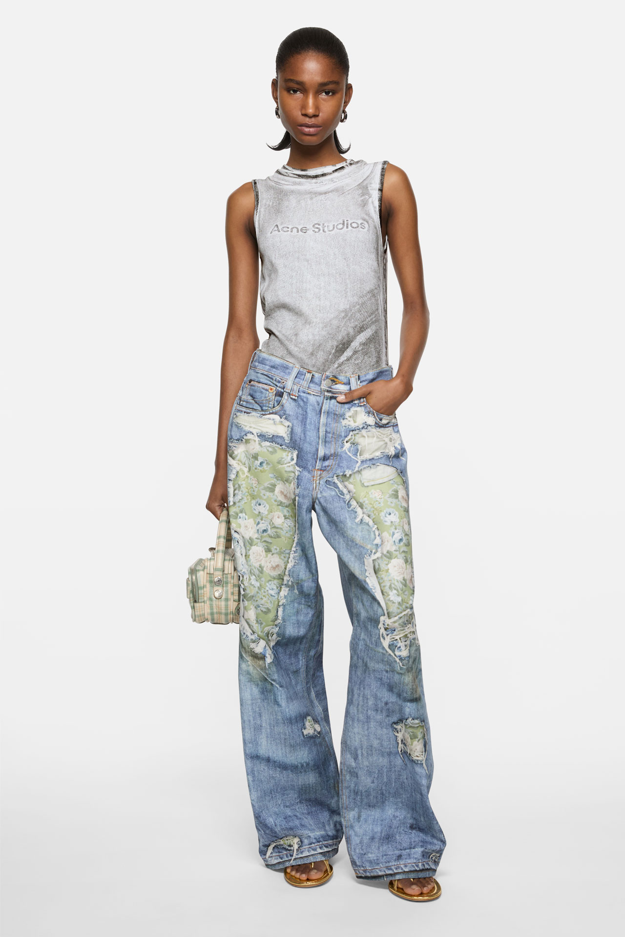 Female model wearing a grey tank-top, blue and green TLO jeans and holding a green Camero bag.