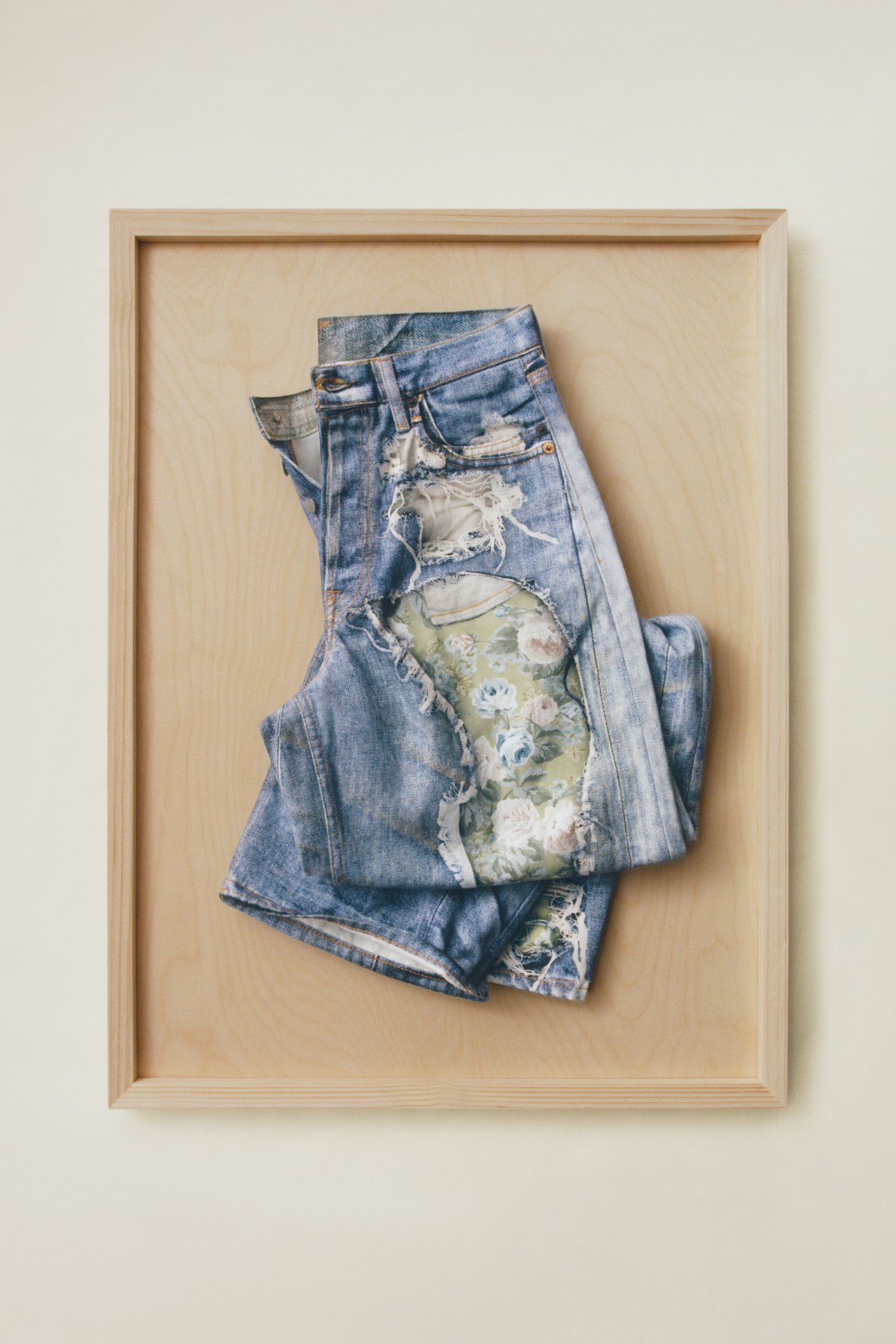 Acne Studios blue floral pattern TLO jeans presented on a wooden tray.